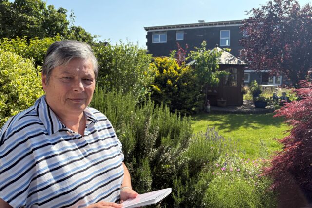 Ute Diedenhofen steht mit einem Notizblock in der Hand im Garten ihres Wohnhauses in Herten-Langenbochum.