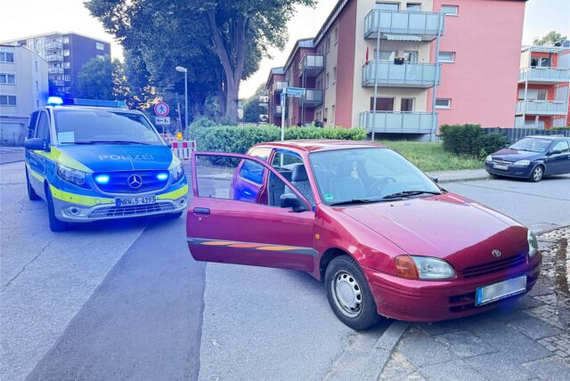Ein rotes Auto steht in Marl vor einem Einsatzwagen der Polizei.
