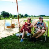 Zwei Frauen und ein kleines Kind sitzen auf Stühlen am Emscherstrand.