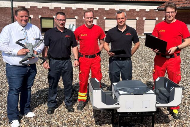Bürgermeister Andreas Stegemann, Feuerwehrchef Michael Dolega, DLRG-Einsatzleiter Sebastian Höhnerhaus, Marvin Bylitza (Sachgebietsleiter Einsatzplanung) und Pascal Sparenberg, Drohnenbeauftragter der DLRG auf dem Dach der Feuerwache Haltern.