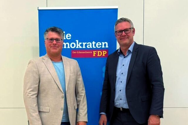 Zwei Männer im Sakko stehen vor einem Werbebanner der FDP.