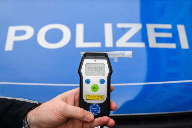 Ein Polizist hält ein Alkoholtestgerät in der Hand.