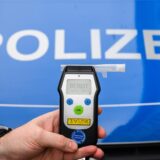 Ein Polizist hält ein Alkoholtestgerät in der Hand.