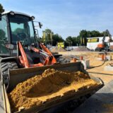 Es ist ein Bagger bei Erdarbeiten zu sehen, während Fundamente für einen Neubau vorbereitet werden.