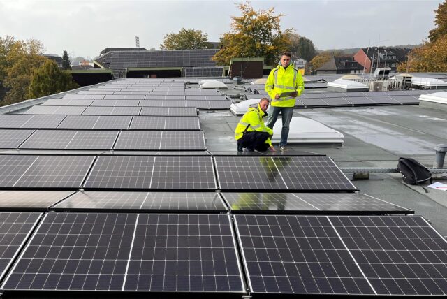 Zwei Mitarbeiter stehen an 80 Modulen auf dem Verwaltungs- und Technikgebäude der Hertener Stadtwerke, die selbst eine beträchtliche Zahl an Solaranlagen betreiben.