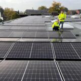 Zwei Mitarbeiter stehen an 80 Modulen auf dem Verwaltungs- und Technikgebäude der Hertener Stadtwerke, die selbst eine beträchtliche Zahl an Solaranlagen betreiben.