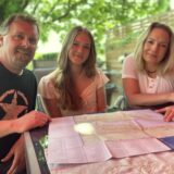Elina Bartz sitzt mit ihren Eltern Ronald und Yvonne vor einer Landkarte von Vancouver.