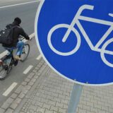 Radfahrer fährt auf einem Radweg an einem Radweg-Schild vorbei