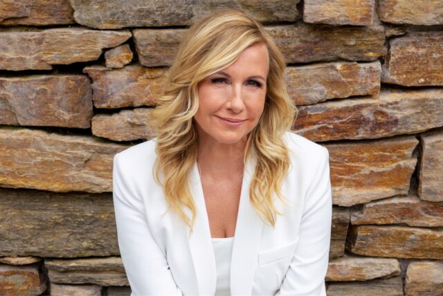 Andrea Kiewel, Moderatorin des ZDF-Fernsehgartens, steht vor einer Naturstein-Mauer.