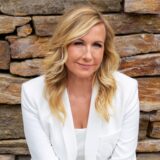 Andrea Kiewel, Moderatorin des ZDF-Fernsehgartens, steht vor einer Naturstein-Mauer.