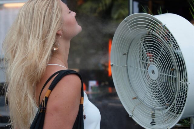Eine Frau erfrischt sich vor einem Ventilator