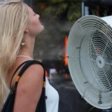 Eine Frau erfrischt sich vor einem Ventilator