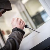 Ein Mann mit einem Schraubendreher hebelt ein Fenster auf.