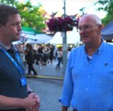 Ein Reporter und VFL Bochum Präsident stehen im Gespräch auf einem belebten Stadtfestplatz; einer berichtet als Präsident des VfL Bochum über Zukunftspläne und seine Verbundenheit zu Castrop-Rauxel.