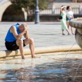 Ein Sportler sitzt erschöpft an einem Brunnen.
