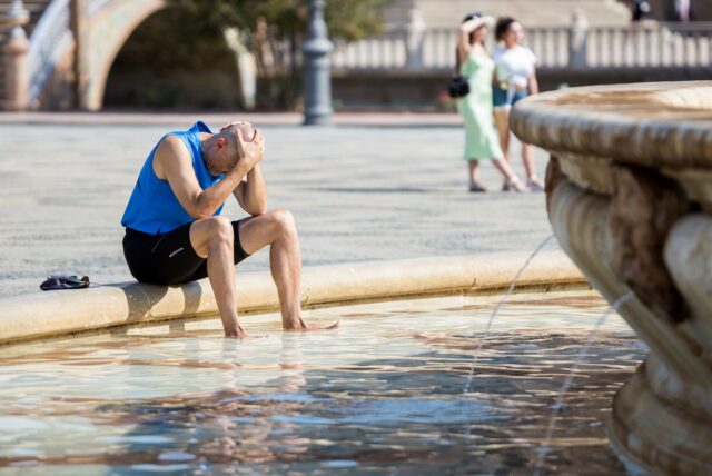 Ein Sportler sitzt erschöpft an einem Brunnen.
