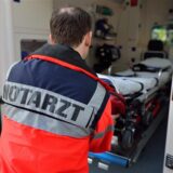 Notarzt steht vor der Tür eines Rettungswagens.