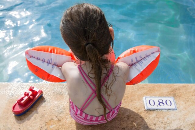 Ein kleines Mädchen trägt Schwimmflügel (Symbolbild).