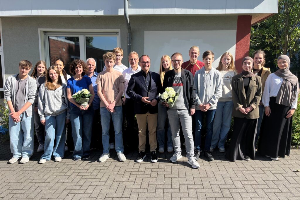 Eine Gruppe von etwa 17 Personen posiert vor einem Gebäude. Einige der Anwesenden halten Blumensträuße. Eine Gruppe von etwa 17 Personen posiert vor einem Gebäude. Einige der Anwesenden halten Blumensträuße.