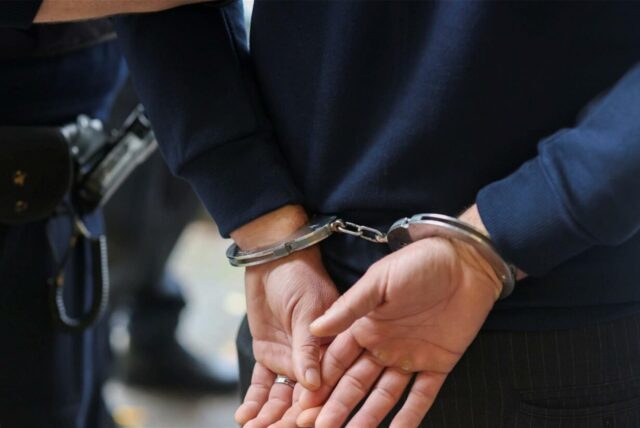 Person wird in Handschellen abgeführt.