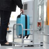 Eine Passagierin prüft in einem Flughafen die Größe ihres Handgepäcks.