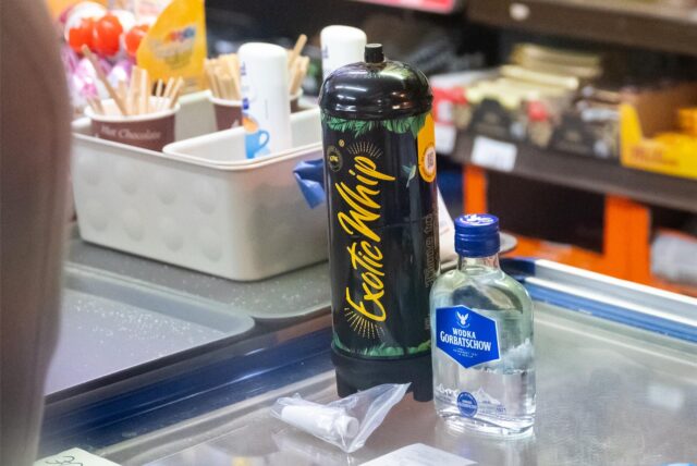 Eine Flasche Lachgas und eine Flasche Wodka auf einem Verkaufstresen in einem Kiosk.