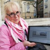 Claudia Ludwig steht auf dem Kirchplatz in Recklinghausen. Sie hält ein Tablet in den Händen.