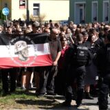 Teilnehmer einer rechtsextremen Demonstration werden von Polizisten begleitet.