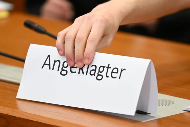 Jemand platziert ein Schild mit der Aufschrift „Angeklagter“.