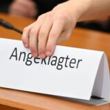 Jemand platziert ein Schild mit der Aufschrift „Angeklagter“.