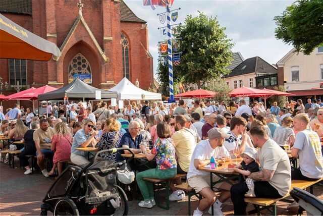 Besucher sitzen an Biergarnituren beim Feierabendmarkt in Haltern