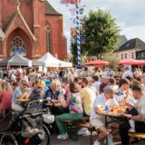 Besucher sitzen an Biergarnituren beim Feierabendmarkt in Haltern