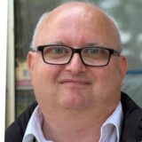 Dargestellt sind drei Porträtaufnahmen von Personen unterschiedlichen Alters und Geschlechts vor einem unscharfen Hintergrund. Die Personen blicken direkt in die Kamera.