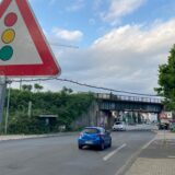 Blick auf die Eisenbahnbrücke über der Kaiserstraße in Herten. Im Hintergrund ist ein Baukran zu sehen, im Bildvordergrund ein Verkehrsschild, dass auf eine Ampel hinweist.