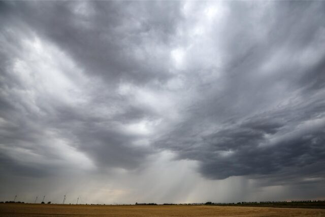 Eine Regenfront zieht über ein Getreidefeld hinweg.