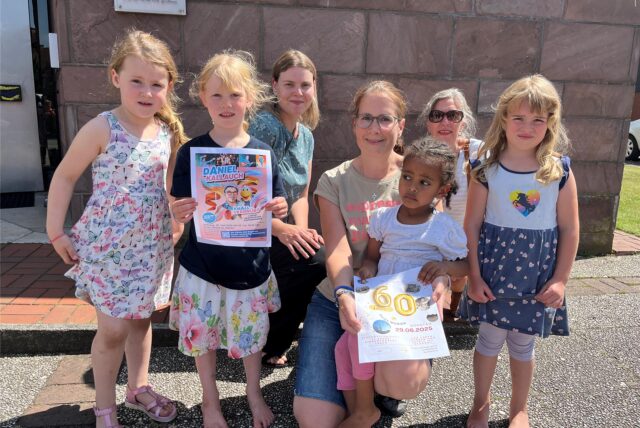 Kinder und Erwachsene mit bunten Ankündigungsplakaten für das Jubiläumsfest in St. Marien.