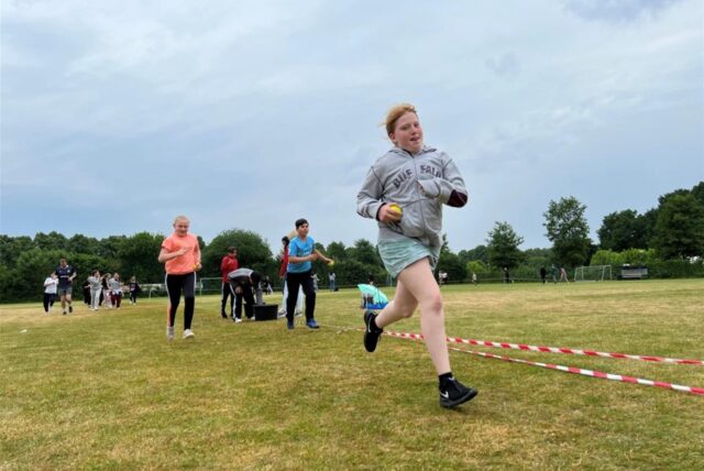 Schülerinnen und Schüler der MLK-Gesamtschule rennen auf einem Sportplatz.