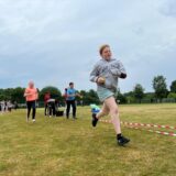 Schülerinnen und Schüler der MLK-Gesamtschule rennen auf einem Sportplatz.