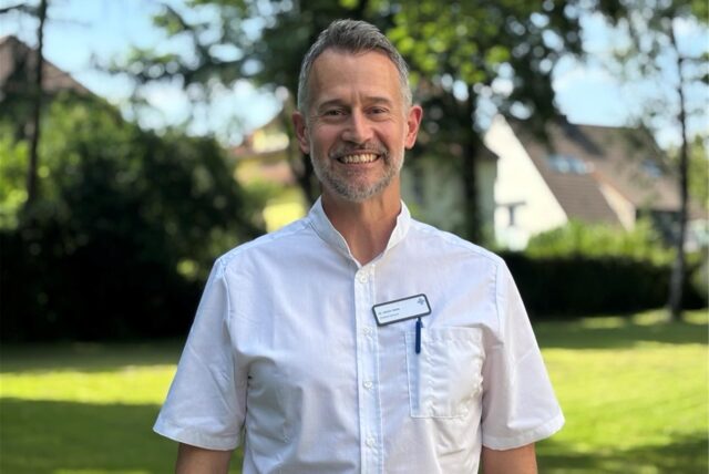 Dr. Ulrich Vahle, Chefarzt der Klinik für Geriatrie am Marienkrankenhaus Schwerte, steht vor einem grünen Hintergrund am Marienkrankenhaus.