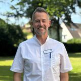 Dr. Ulrich Vahle, Chefarzt der Klinik für Geriatrie am Marienkrankenhaus Schwerte, steht vor einem grünen Hintergrund am Marienkrankenhaus.