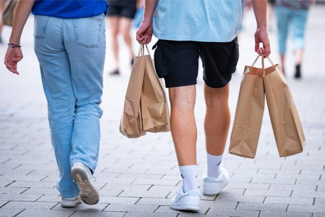 Passanten gehen am verkaufsoffenen Sonntag mit Einkaufstüten durch die Innenstadt.