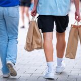 Passanten gehen am verkaufsoffenen Sonntag mit Einkaufstüten durch die Innenstadt.