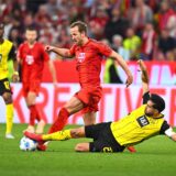 Spielszene aus einem Fußballspiel zwischen Bayern München (in Rot) und Borussia Dortmund (in Gelb), ein Dortmunder Spieler grätscht gegen einen Bayern-Spieler um den Ball.