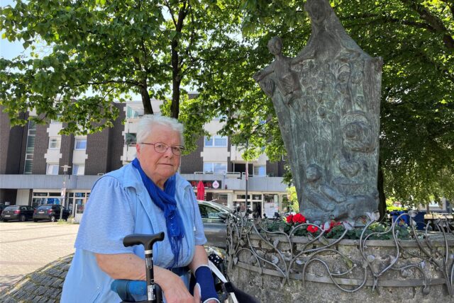 Anwohnerin in Herten-Mitte, mit Rollator am Denkmal „Schutzmantelmadonna“