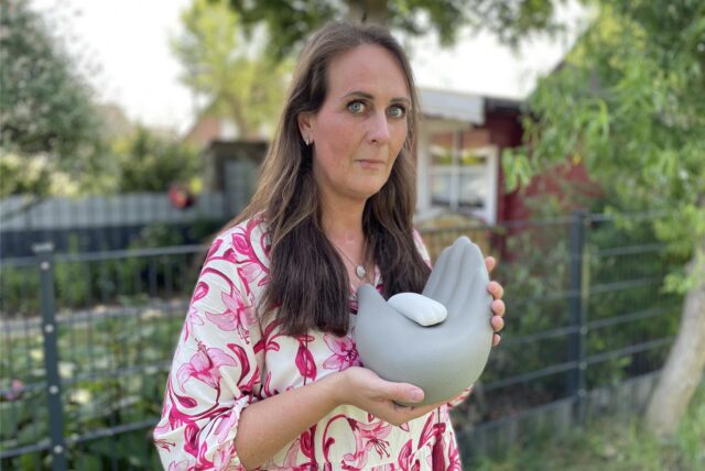 Die Dortmunderin Christina Prinz hält die Urne mit der Asche ihres verstorbenen Hundes Riku in den Händen.