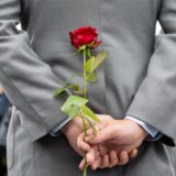 Ein Mann hält eine Rose hinter dem Rücken.