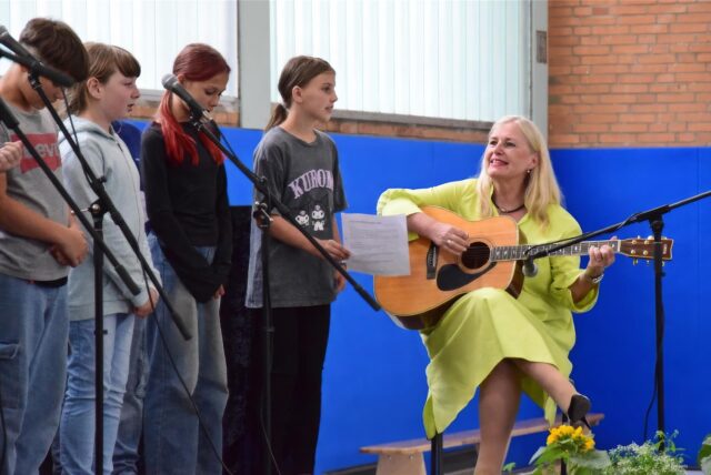 An der Gitarre: Schulleiterin Dagmar Perret, dazu singen Schülerinnen und Schüler der Klassen 5 und 6.