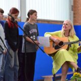 An der Gitarre: Schulleiterin Dagmar Perret, dazu singen Schülerinnen und Schüler der Klassen 5 und 6.