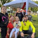 Eltern sitzen mit ihren Kindern auf der Wiese.