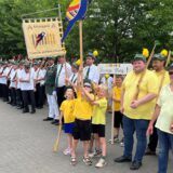 Kinder halten ein Banner hoch mit einem Papagei bestickt.
